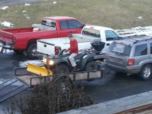 A man is loading up his atv on the trailer.
